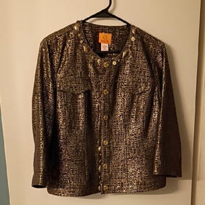 May include: A gold and black textured jacket with long sleeves, a button-up front, and two chest pockets. The jacket has gold-colored buttons and decorative accents on the collar. The Ruby Rd. brand tag is visible.