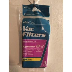Pode incluir: Um pacote de filtros de vácuo Ultra Care para aspiradores Kenmore EF-2. A embalagem azul e roxa exibe "Vac Filters" e "HEPA Media". Projetado para aspiradores Kenmore de depósito e verticais. Pendurado em um gancho de metal.
