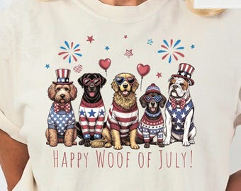 May include: An ivory t-shirt featuring a graphic of five dogs wearing patriotic sweaters, hats, and heart-shaped sunglasses. The design includes red, white, and blue stars, fireworks, and heart balloons with the text "HAPPY WOOF OF JULY!" printed below.