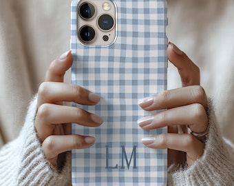 May include: A light blue and white gingham patterned phone case featuring the letters LM in a serif font centered near the bottom. The case has a cutout for a triple camera system and is designed to fit a smartphone with a rectangular shape.