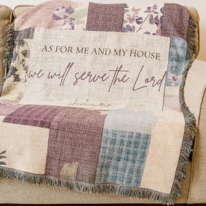 May include: A patchwork throw blanket in shades of purple, beige, and blue, with fringed edges. The blanket features the text "AS FOR ME AND MY HOUSE we will serve the Lord" and the reference Joshua 24:15.