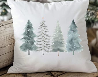May include: White square throw pillow featuring a watercolor design of four stylized Christmas trees in shades of blue and gray. The trees have a star on top. The pillow is placed on a wooden surface.
