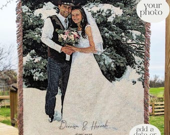 May include: A woven throw blanket featuring a black and white photographic print of a couple in wedding attire standing in a snowy landscape. The blanket includes the text "Denniza & Hannah" and "EST 2020" with fringed edges on the sides.