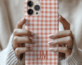 May include: A smartphone case featuring a light orange and white gingham check pattern. The case has a cutout for a triple-lens camera system in the upper left corner and the capital letters JM printed in a serif font in the lower center area.
