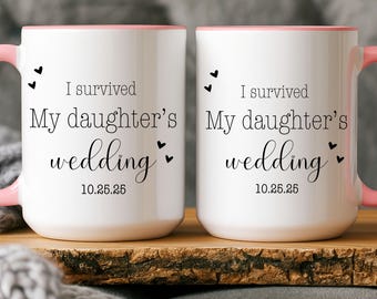 May include: Two white ceramic mugs with pink interiors and handles. The mugs feature black text that reads I survived My daughter's wedding 10.25.25, accented with small black heart icons. The design is printed on both sides of each mug.