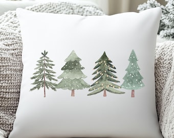 May include: White square throw pillow featuring a watercolor design of four Christmas trees in varying shades of green. The trees have brown trunks and some are decorated with white snow and lights. A cozy holiday theme.