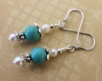 Op de afbeelding: Turquoise en witte kralen oorbellen met zilveren accenten en oorhaakjes.