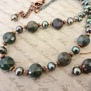 May include: A green and black gemstone necklace and earrings set with copper accents. The necklace features round green and black beads with copper spacers. The earrings are dangle earrings with a green gemstone and copper accents.