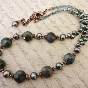 May include: A necklace with dark green and gray gemstone beads, copper spacers, and dark gray pearls.