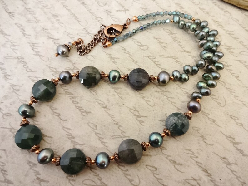 May include: A necklace with dark green and gray gemstone beads, copper spacers, and dark gray pearls.
