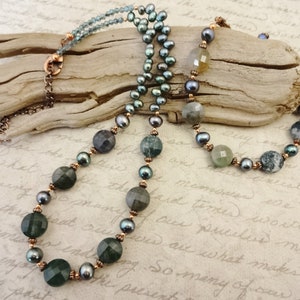 May include: A multi-strand necklace with green agate beads, freshwater pearls, and copper spacers. The necklace is displayed on a piece of driftwood.