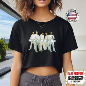 May include: Black crop top featuring the word "Millennium" and an image of five men in white outfits. A "Made in the USA" sticker is visible. The shirt also has a "Fast Shipping" graphic.