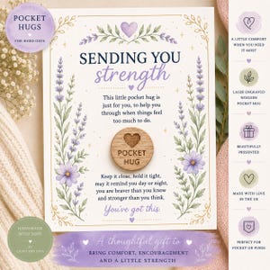May include: A circular wooden token engraved with a heart and the text POCKET HUG, centered on a rectangular card featuring lavender illustrations and the text SENDING YOU strength. The card includes encouraging phrases and decorative gold borders.