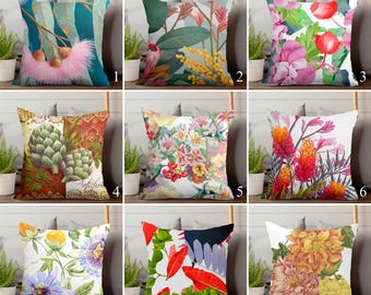 May include: Nine decorative throw pillows with floral and botanical designs. The pillows feature various colorful patterns, including flowers, leaves, and abstract shapes. The pillows are square and appear to be made of fabric.