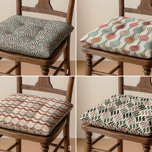 Può includere: Quattro cuscini quadrati per sedie con diversi motivi. Il primo ha un motivo floreale grigio e rosso. Il secondo ha un motivo ripetuto di forme rosse, arancioni e verdi. Il terzo ha un motivo a onde rosse e grigie. Il quarto ha un motivo a onde verdi e marroni.