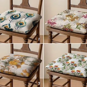 Puede incluir: Cuatro cojines cuadrados para silla con centros capitoné, cada uno con un patrón distinto: plumas de pavo real, orquídeas florales, crisantemos amarillos y ramas botánicas con puntas rojas. Cada cojín está sobre una silla de madera, numerado del 1 al 4.