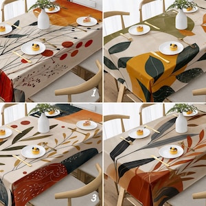 May include: Four rectangular tablecloths with abstract botanical designs in various color palettes. Each tablecloth features a different pattern of leaves, branches, and geometric shapes in shades of orange, green, and brown. The tablecloths are set on wooden tables with place settings.