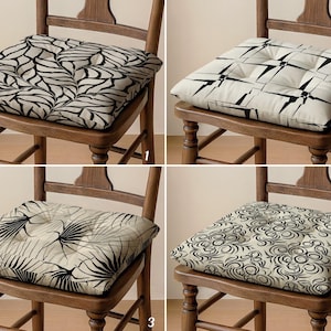 May include: Four square chair cushions with different black and white patterns. The cushions are on wooden chairs. The patterns include leaf-like designs, geometric shapes, and swirling lines. Each cushion is button-tufted.