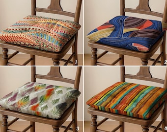 May include: Four square chair cushions with various colorful patterns. The cushions are placed on wooden chairs. The patterns include geometric designs, abstract shapes, and striped patterns. The cushions add a decorative element to the chairs.
