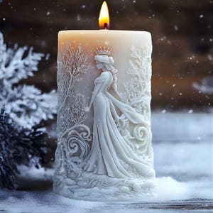 May include: An ivory pillar candle with a detailed relief carving of a princess in a flowing gown and crown, surrounded by wintery trees. The candle is lit, with a warm flame. The scene is set against a snowy backdrop.