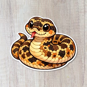 May include: A cartoon sticker of a snake with a brown and tan pattern. The snake has large, friendly eyes and a red tongue sticking out. The sticker is on a white background.
