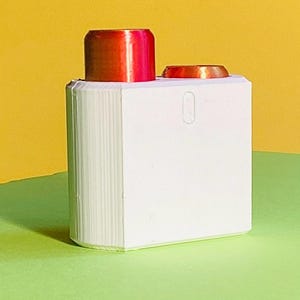 Peut inclure: Un objet rectangulaire blanc avec un côté strié, surmonté de deux cylindres de couleur cuivre. Un cylindre est plus grand et rouge, l'autre est plus petit et orange. Le fond est jaune et vert.