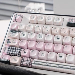 May include: A set of three ceramic mugs with a speckled, matte finish. The mugs are in shades of cream, light gray, and dark gray. Each mug has a simple, minimalist design and a rounded handle.