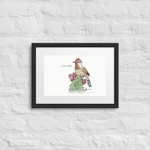 May include: Framed art print featuring a detailed illustration of a Cactus Wren perched on a cactus with pink flowers. The artwork is set against a white background, with the words "CACTUS WREN" above the bird. The print is in a black frame.