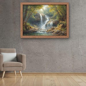 May include: A framed landscape painting depicts a waterfall cascading into a pool, surrounded by lush greenery. The artwork is set in a wooden frame and hangs on a gray concrete wall. A neutral-toned armchair and side table with decor are in the foreground.