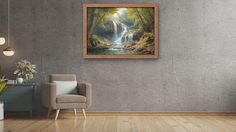May include: A framed landscape painting depicts a waterfall cascading into a pool, surrounded by lush greenery. The artwork is set in a wooden frame and hangs on a gray concrete wall. A neutral-toned armchair and side table with decor are in the foreground.