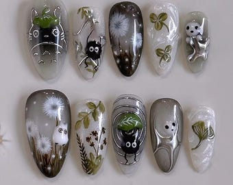 Könnte beinhalten: Ein Set aus zehn künstlichen Nägeln mit verschiedenen Designs. Die Designs umfassen Zeichentrickfiguren, Löwenzahnpflanzen und florale Muster. Die Nägel sind oval geformt und haben ein glänzendes Finish mit silbernen Akzenten.