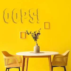 May include: A yellow wall features the word OOPS! in a bold, dripping font. Below, a round white table holds a textured gray vase with green eucalyptus branches. Two yellow chairs with slatted backs flank the table, and two empty wooden frames hang on the wall.