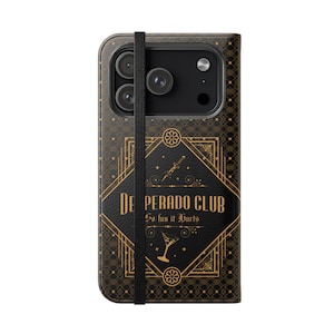May include: A black and gold phone case featuring a geometric diamond pattern and the text "DESPERADO CLUB So fun it Hurts". The design includes a small dagger and a martini glass icon, with a vertical black elastic strap running down the center.