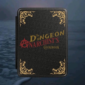 May include: A black book with gold corner designs and the title "The Dungeon Anarchist's Cookbook" in red and gold lettering. The book has a textured cover and an anarchist symbol.