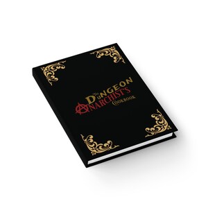 May include: A black hardcover book titled "The Dungeon Anarchist's Cookbook." The cover features gold decorative corner designs and red and gold lettering. The book is angled, showing the cover and a portion of the white-edged pages.