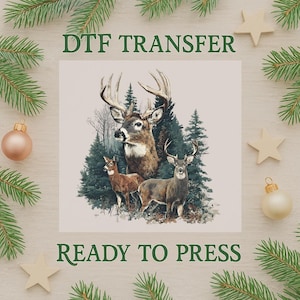 Könnte beinhalten: Ein DTF-Transfer mit einer detaillierten Illustration von drei Hirschen in einer Waldlandschaft. Das Bild enthält den Text "DTF TRANSFER" und "READY TO PRESS" in Grün. Das Design ist von Weihnachtsschmuck und Tannenzweigen umgeben.