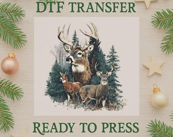 Op de afbeelding: Een DTF-transfer met een gedetailleerde illustratie van drie herten in een bosrijke omgeving. De afbeelding bevat de tekst "DTF TRANSFER" en "READY TO PRESS" in het groen. Het ontwerp is omgeven door kerstversieringen en dennentakken.