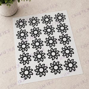 May include: A sheet of white stickers featuring a repeating pattern of black sunburst designs. Each sunburst has a central circle with radiating petal-like shapes. The stickers are arranged in rows and columns.