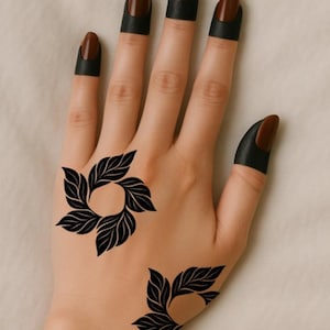 May include: A hand decorated with black henna floral patterns and dark brown nail polish. The henna art features leaf-like designs. The fingernails are painted a dark brown colour with black bands at the base of the nails.