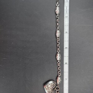 May include: Silver-toned bracelet with a teardrop-shaped charm that reads "MOM" and a heart-shaped charm. The bracelet is approximately 9 inches long and features a chain with decorative links. A ruler is next to the bracelet.