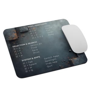 Könnte beinhalten: Rechteckiges Mauspad mit einem Design aus abgenutztem Metall und weißem Text, der grundlegende Computerfunktionen und Verknüpfungen detailliert. Eine weiße kabellose Maus liegt auf der rechten Seite. Das Pad ist für iOS konzipiert.
