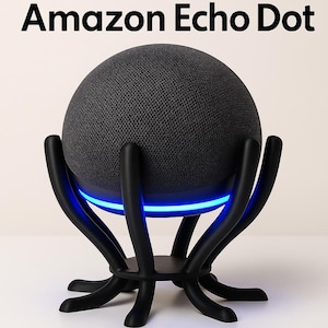 May include: A black Amazon Echo Dot smart speaker in a black stand with a blue light. The stand has a unique design with multiple curved arms. The text "Amazon Echo Dot" is at the top of the image.
