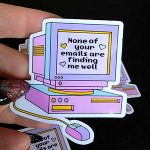 Op de afbeelding: Een sticker met een retro computerontwerp in pastelkleuren. Het scherm toont de tekst "None of your emails are finding me well" met hartjes. Inclusief een muis en kabel.