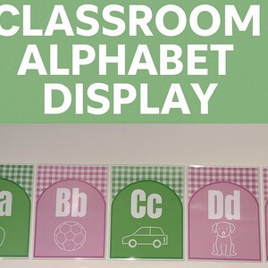 Pode incluir: Exibição do alfabeto da sala de aula com painéis verdes e rosa. Cada painel apresenta uma letra do alfabeto com uma imagem correspondente. As letras são brancas e o fundo é um padrão xadrez. A parte superior da imagem tem o texto "CLASSROOM ALPHABET DISPLAY".