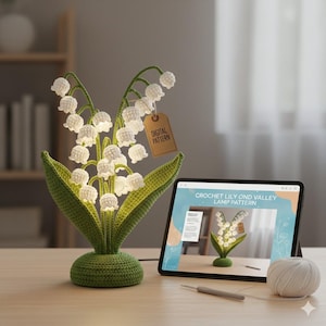 Könnte beinhalten: Gehäkelte Maiglöckchen-Lampe mit weißen Blütenknospen und grünen Blättern. Die Lampe hat einen grünen Sockel und Stiel. Ein Anhänger trägt die Aufschrift "DIGITAL PATTERN". Ein Tablet zeigt "CROCHET LILY OND VALLEY LAMP PATTERN".