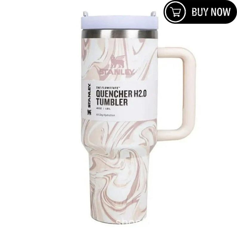 May include: A stainless steel Stanley Quencher H2.0 Tumbler with a white and pink marble design. The tumbler has a white handle and lid, and the text "QUENCHER H2.0 TUMBLER" is printed on the front. It holds 40 oz (1.18 L).