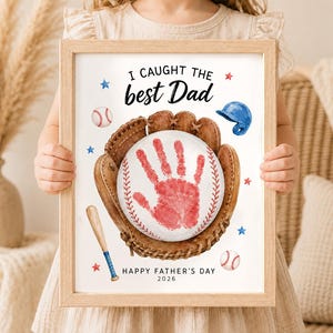 May include: A framed print featuring a brown baseball glove holding a white baseball with a red handprint in the center. The text reads I CAUGHT THE best Dad and HAPPY FATHER'S DAY 2026, surrounded by illustrations of a baseball bat, helmet, and stars.