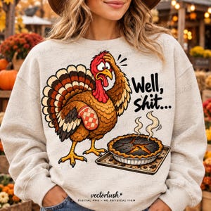 May include: A light heather gray sweatshirt featuring a cartoon turkey with a red wattle and a red and white checkered oven mitt on its wing. The turkey looks stressed, with the text Well, shit... above a burnt pie on a baking sheet.
