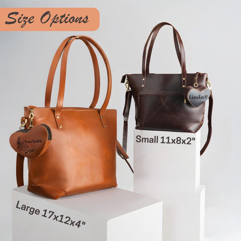 May include: Two leather tote bags in different sizes, one large and one small, displayed on white pedestals. The large bag is tan, measuring 17x12x4 inches, and the small bag is dark brown, measuring 11x8x2 inches. Both have heart-shaped charms.