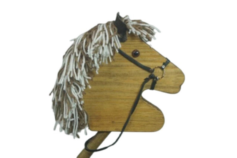 May include: Wooden toy horse head with a brown and white mane and a black leather bridle. The horse head is attached to a wooden stick.
